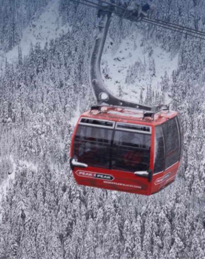 Gondola suspended above snow‑covered mountains.