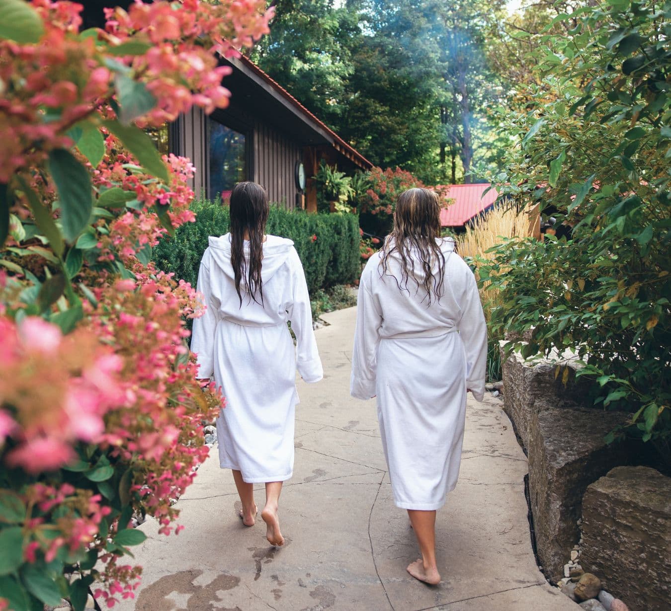 Two people exploring Scandinave Spa Blue Mountain, walking surrounded by flowers.