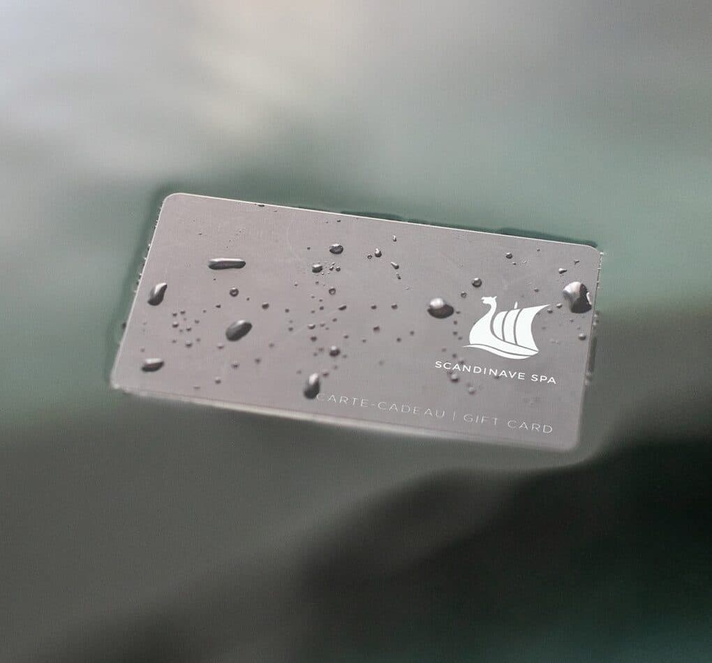 Scandinave Spa gift card resting on a surface with water droplets, representing a spa experience gift.
