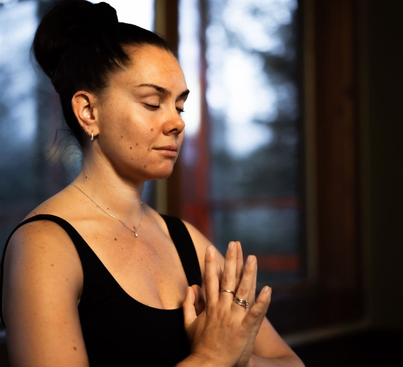 Person with eyes closed and hands together in an indoor spa wellness and relaxation space.