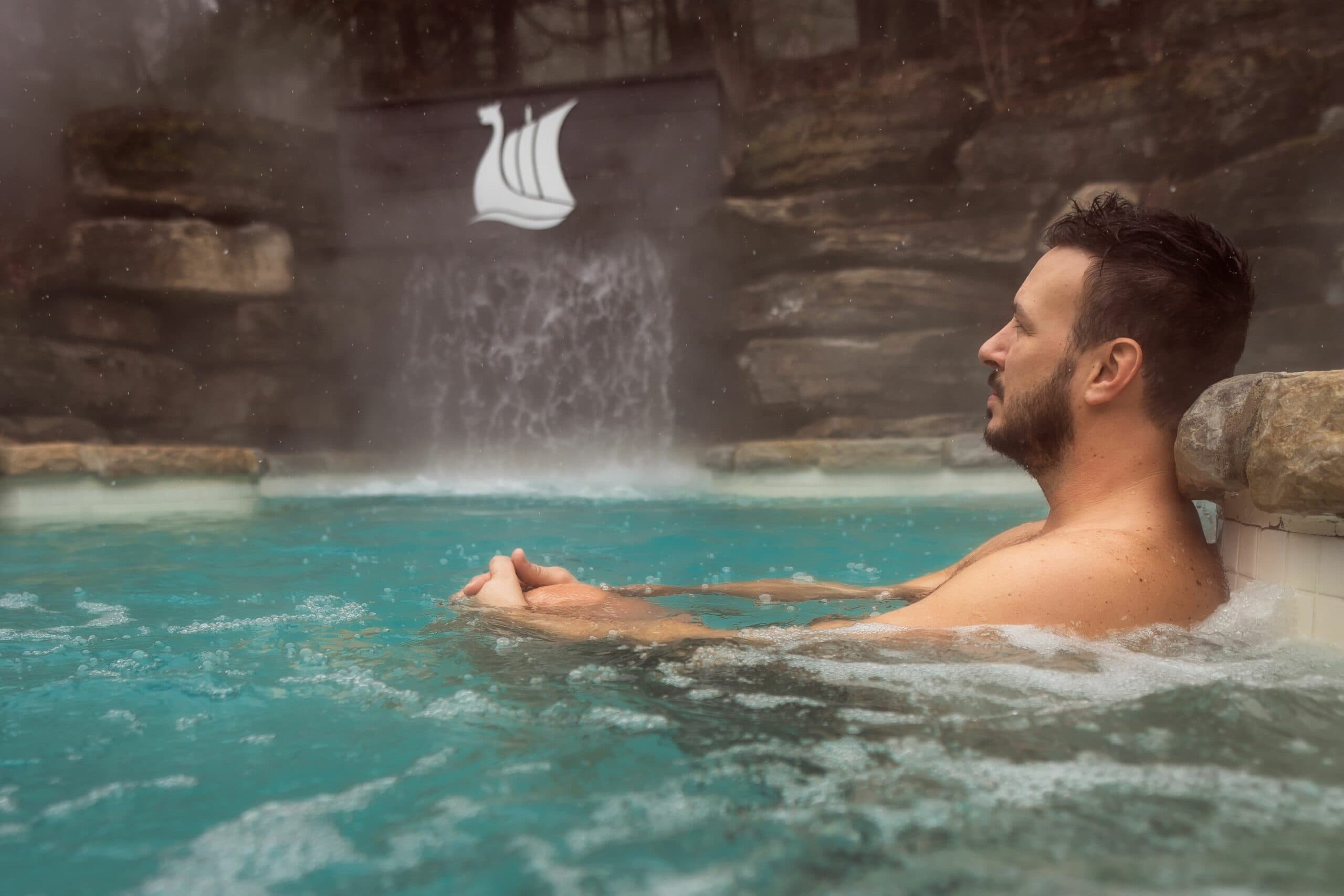 A man relaxing in an outdoor thermal pool at Scandinave Spa