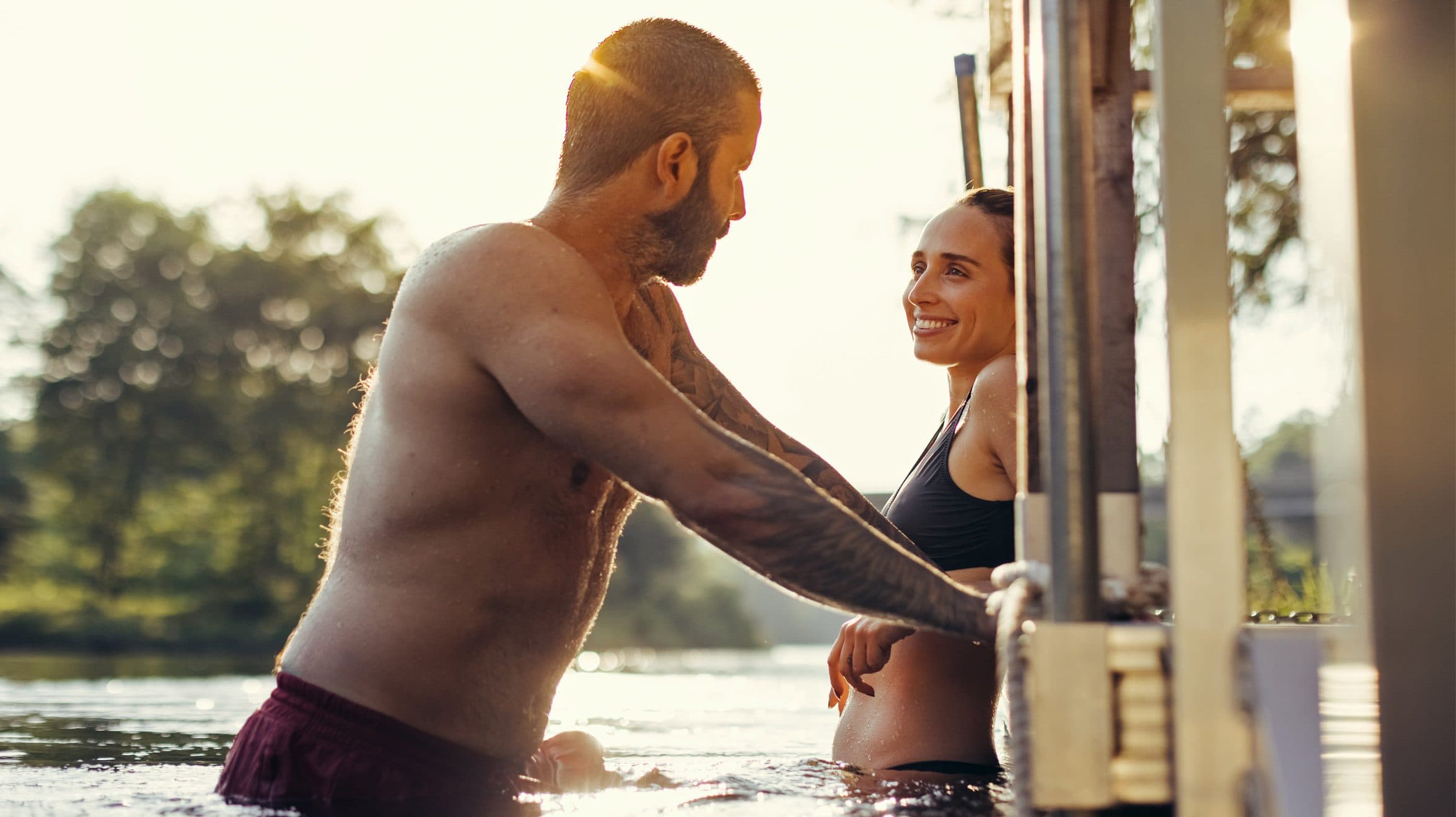 A couple smiling at each other during the summer golden hour on the Diable River at Scandinave Spa Mont-Tremblant.