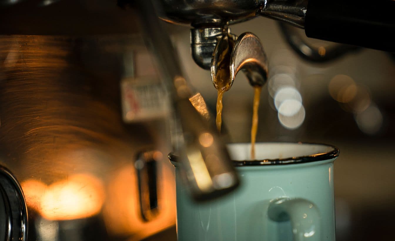 Espresso pours into a mug with an early morning glow at Scandinave Spa Whistler.