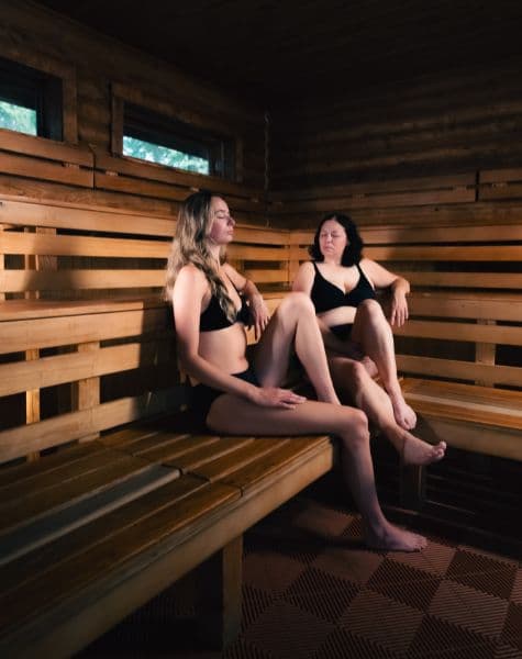 Two women sitting with eyes closed in a sauna at Scandinave Spa Mont-Tremblant, enjoying deep relaxation and silence