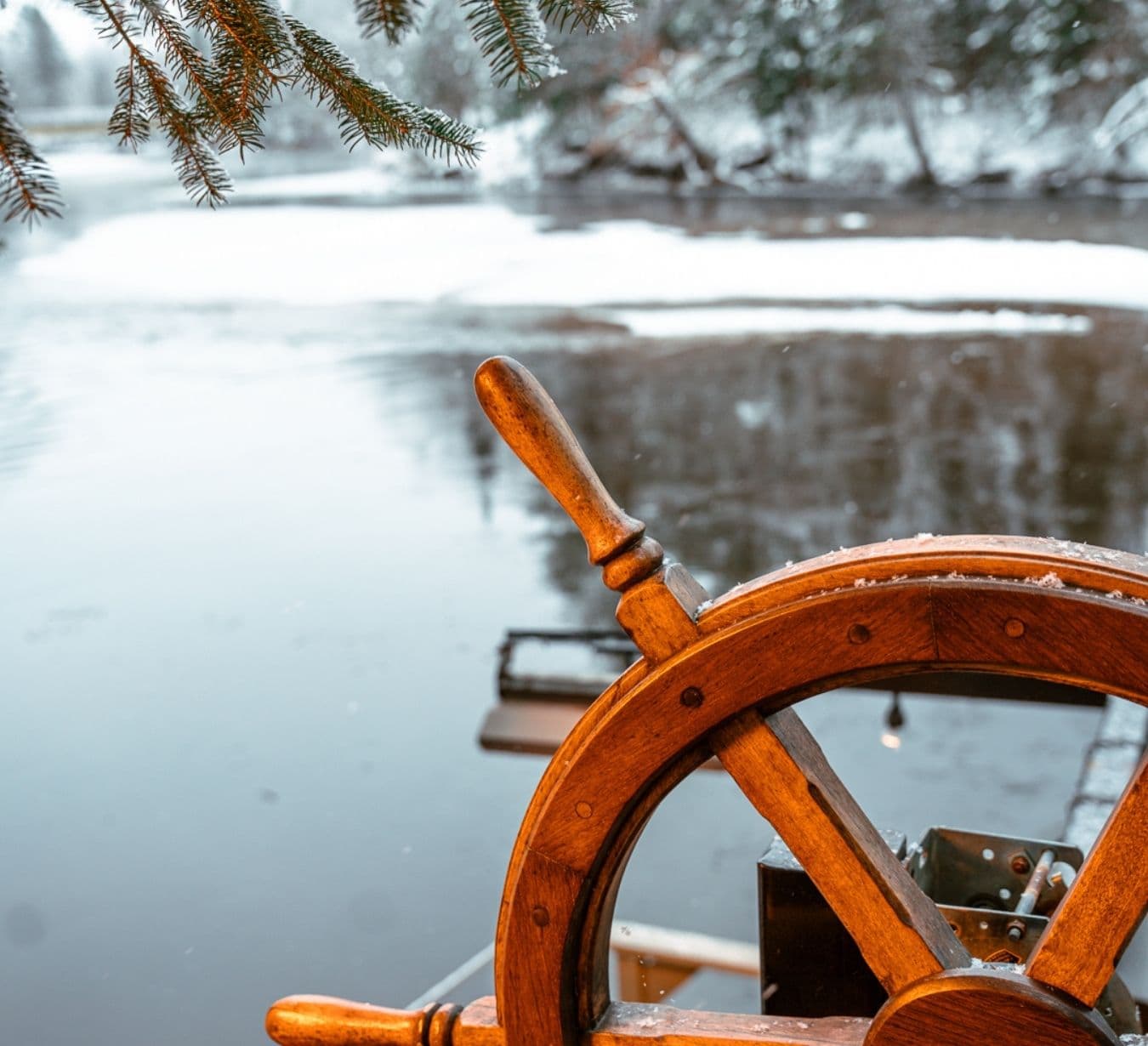 Gros plan d'un gouvernail en bois avec, en arrière-plan, la rivière du Diable gelée.
